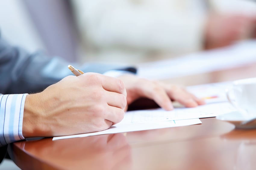 Image of businessmans hands signing documents at meeting